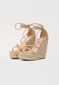 Nude kilehæle sandaler med flettet jute-sål, der har en struktureret platform og tynde crisscross-remme. Metalliske detaljer på sålen.