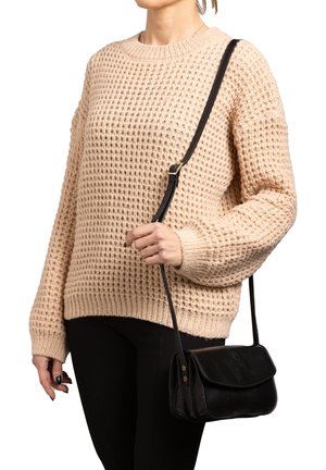 Maglione beige lavorato a maglia con una vestibilità morbida e un motivo strutturato, abbinato a una piccola borsa a tracolla nera con pattina e dettagli di cucitura.
