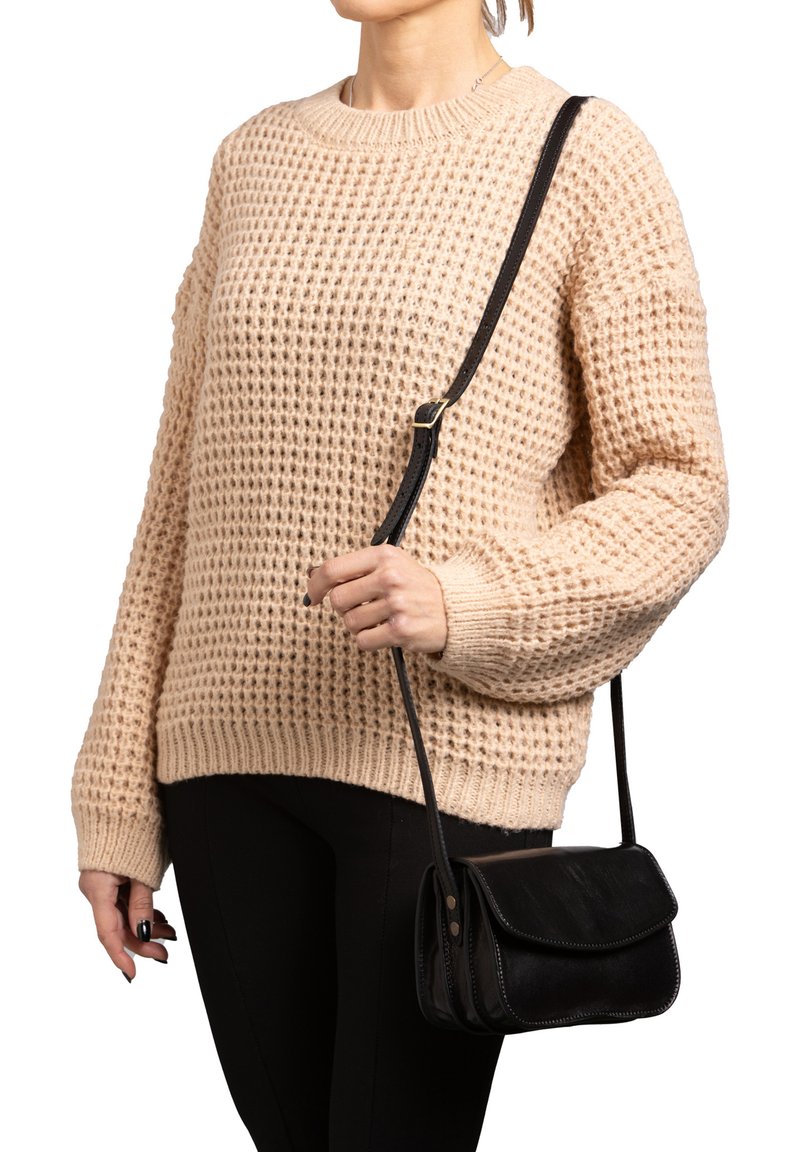 Maglione beige lavorato a maglia con una vestibilità morbida e un motivo strutturato, abbinato a una piccola borsa a tracolla nera con pattina e dettagli di cucitura.