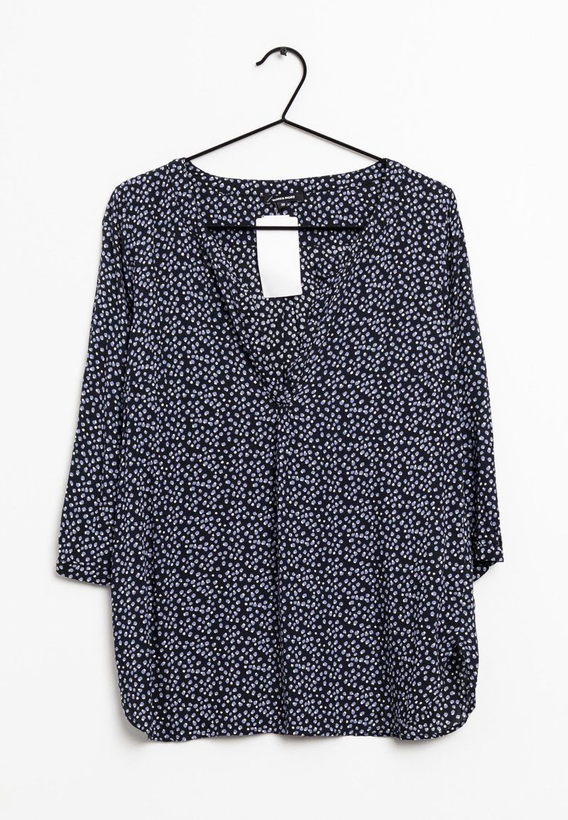 Blouse marine à manches trois-quarts, avec des pois blancs et bleu clair, en tissu léger, design en col en V, et une étiquette pendante à l'arrière.