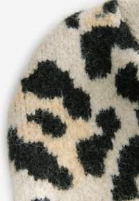 Wollen stof met een beige achtergrond en grote zwarte dierenprintvlekken. Zachte textuur met een viltachtige oppervlakte en een contrasterend gedurfd patroon.