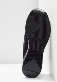 Schwarzer Sneaker mit strukturierter Gummisohle. Verfügt über ein geschwungenes Design und ein geprägtes Logo mit einem profilierten Absatz für besseren Halt.