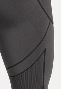 Hochwertige schwarze Leggings aus glattem Stoff mit kontrastierenden, strukturierten Streifen und einem schlanken, figurbetonten Design mit geometrischen Akzenten.