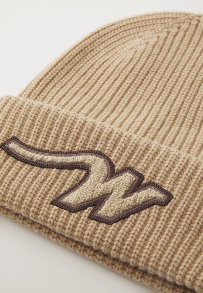Beige knitted beanie with a ribbed texture, featuring a prominent embroidered "W" logo in brown and cream accents.