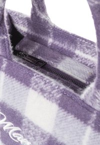 Lila karierte Handtasche aus weichem Stoff, ausgestattet mit einem Reißverschluss und schwarzen Beschlägen. Das Innere hat eine flauschige Textur und ein Markenetikett.