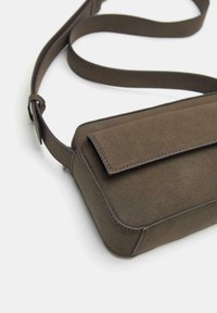 Borsa a tracolla marrone con superficie testurizzata, forma rettangolare, chiusura a patta e tracolla regolabile. Presenta cuciture a contrasto lungo i bordi.