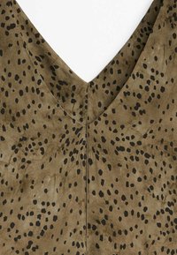 Tissu en suède marron avec un décolleté en V et un motif noir à taches dispersées ; une couture nette descend le long du dos. Texture lisse dans l'ensemble.