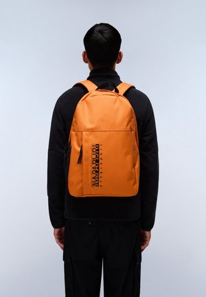 Sac à dos orange avec un logo noir, doté de bretelles rembourrées et d'une poche latérale zippée. Matériau lisse et forme rectangulaire.