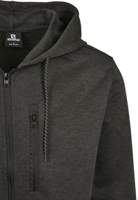 Felpa con zip di un grigio scuro, dal texture morbido, dotata di cappuccio regolabile con coulisse, tasche con zip e dettagli neri sulle spalle.