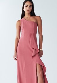 Abito rosa monospalla con corpetto aderente, dettaglio asimmetrico a ruches e spacco alto sulla coscia. Tessuto liscio.