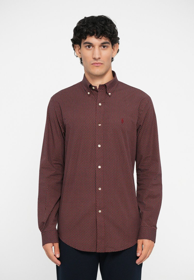 Cămașă cu mânecă lungă în carouri roșii și bleumarin, cu guler tip button-down, având un buzunar cu un logo mic și butoane albe pe placket.