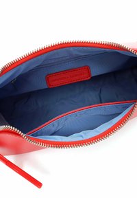 Neceser rojo con cremallera y un exterior suave. El interior cuenta con un forro azul claro y una etiqueta de cuero etiquetada "SURI FREY × ALEXANDER."