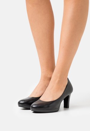 Chaussures à talons hauts en cuir noir avec un bout arrondi et une légère plateforme. Texture lisse, design fuselé et talon en bloc robuste.