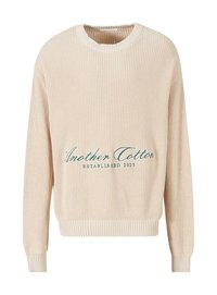 Beige striktrøje med ribbet tekstur, rund halsudskæring og lange ærmer. Har grøn broderet tekst: "Another Cotton ETABLERT 2023."