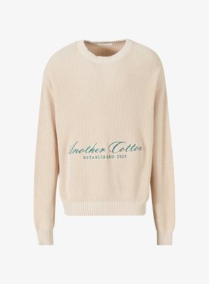 Beige Strickpullover mit gerippter Struktur, Rundhalsausschnitt und langen Ärmeln. Mit grüner gestickter Aufschrift: "Another Cotton ESTABLISHED 2023."
