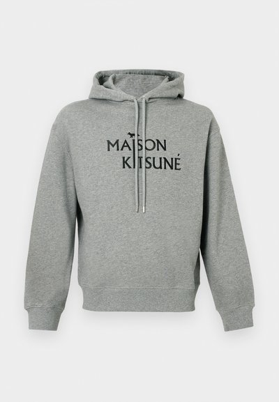 Hanorac gri dintr-un material moale, cu o buzunar tip kangaroo în față, șnururi pentru ajustare și un logo negru "MAISON KITSUNÉ" însoțit de o mică pictogramă a unei vulpi.