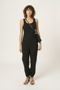 Black fitted tank top with textured detail, paired with loose black pants featuring elastic cuffs, complemented by black heeled sandals.