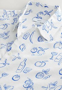 Chemise à manches courtes en tissu blanc ornée d'illustrations de fruits et de boissons bleues ; col classique, fermeture à boutons et design décontracté.
