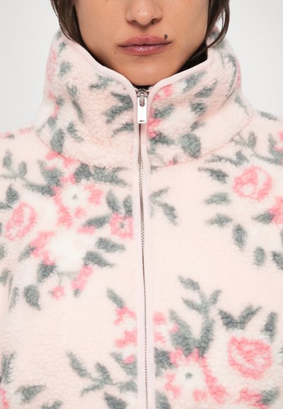 Fleecová bunda v jemnej ružovej farbe s kvetinovými vzormi v zelenej a ružovej farbe. Má vysoký golier a predný zips.