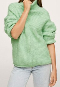 Pull vert clair en maille avec un col haut et des manches oversize ; tissu texturé avec un motif côtelé et une coupe décontractée.