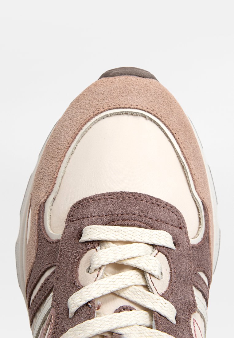 Sneaker caratterizzata da un mix di pelle beige chiaro e suede rosa polveroso, punta rotonda, lacci bianchi, accenti marrone scuro a contrasto, superficie testurizzata.