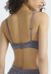 Šedá podprsenka s texturovaným květinovým vzorem, nastavitelnými ramínky a zapínáním na háček vzadu. Hladká látka s jemným povrchem.