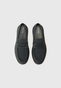 Sorte slip-on sko med en glatt lærøvre, rund tå og minimal søm. Myk innerlining med merkevaren logo synlig på sålen.