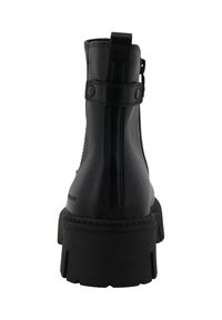 Botas de cuero negras hasta el tobillo con una suela gruesa y resistente, cierre de cremallera lateral y una tira de tracción para facilitar el uso. Presenta detalles de costura visibles.