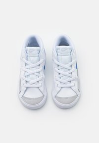 Vita Nike-sneakers med ljusblå detaljer, texturerade grå mockadelar och vita snören, utrustade med en vadderad tunga och mjukt inre.