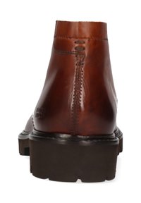 Botín de cuero marrón con textura lisa, punta redonda y suela negra gruesa. Presenta costuras mínimas y detalles en el tacón.