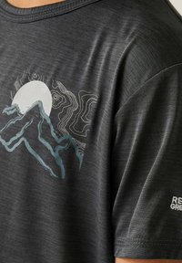 Dunkelgraues T-Shirt mit rundem Ausschnitt, das auf der linken Schulter einen Grafikdruck von einem Berg und der Sonne in Hellblau und Weiß zeigt.