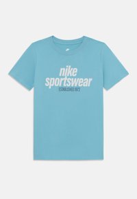 Šviesiai mėlynas medvilninis marškinėliai trumpomis rankovėmis ir apvalia iškirpte, priekyje turi baltą grafikos logotipą "nike sportswear ESTABLISHED 1972".