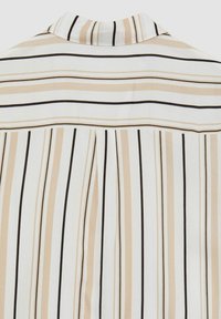 Camicia a righe con righe verticali in beige, bianco e nero. Tessuto morbido con colletto e design con pieghe sulla schiena.