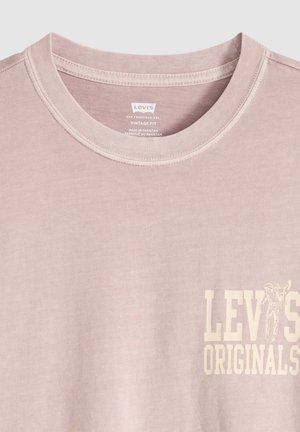 T-shirt Levi's Originals vintage rose clair à col rond avec logo et motif sur la poitrine, fabriqué au Pakistan.