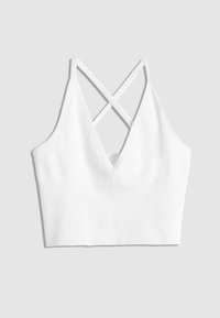Hvid ribbet bralette med dyb V-hals, der har krydset stropper på bagsiden. Glat texture og tætsiddende design.