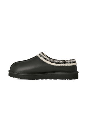 Chausson noir à enfiler avec semelle rembourrée, doublure en fausse fourrure blanche et bordure décorative cousue autour de l’ouverture.