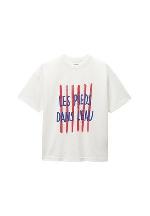 T-shirt blanc à manches courtes avec texte français bleu "Les Pieds Dans L'eau" sur cinq lignes verticales de coups de pinceau rouges à l’avant.