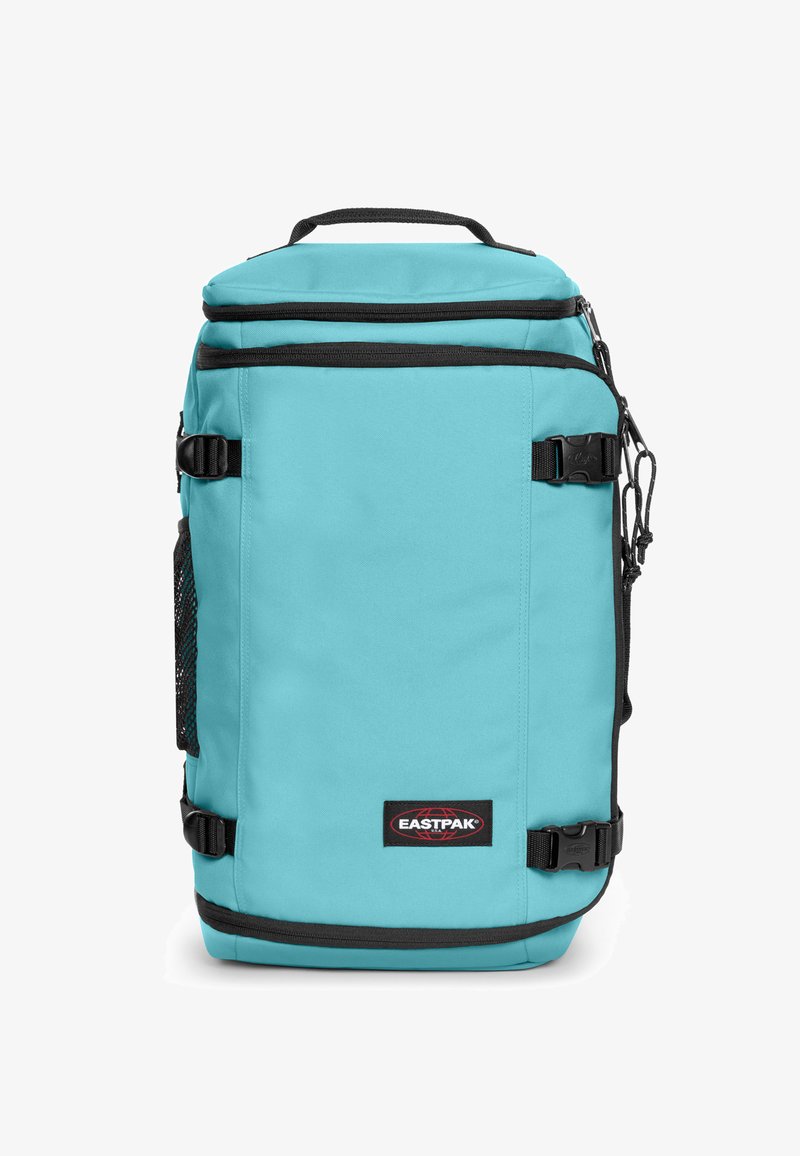 Sac à dos turquoise avec des accents noirs, fabriqué en tissu durable. Dispose d'une poche frontale en mesh, d'une poignée supérieure et de bretelles réglables.