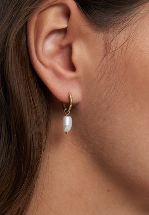 Gold hoop earrings with a suspended irregular white pearl. The pearl has a smooth texture, and the hoop features a shiny finish.