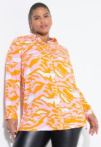 Chemise à manches longues en imprimé animal orange et rose, avec un devant à boutons, un col étalé et une coupe décontractée. Texture de tissu lisse.