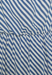 Niebiesko-biały materiał w paski z zygzakowatym wzorem, z marszczeniami w talii.