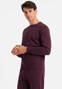 Lila Crewneck-Sweatshirt mit gerippten Bündchen und Saum, aus einem weichen, strukturierten Stoff, kombiniert mit passenden Hosen.