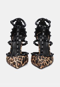 Sandalias con tacón que presentan un estampado de leopardo, con un diseño de tiras de cuero sintético negro adornado con picos metálicos.