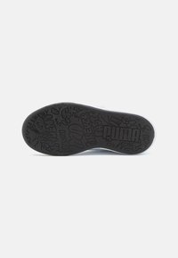 Sole in gomma nera con motivi grafici, con il logo "PUMA" ben in evidenza. La suola presenta texture diverse e design dettagliati.