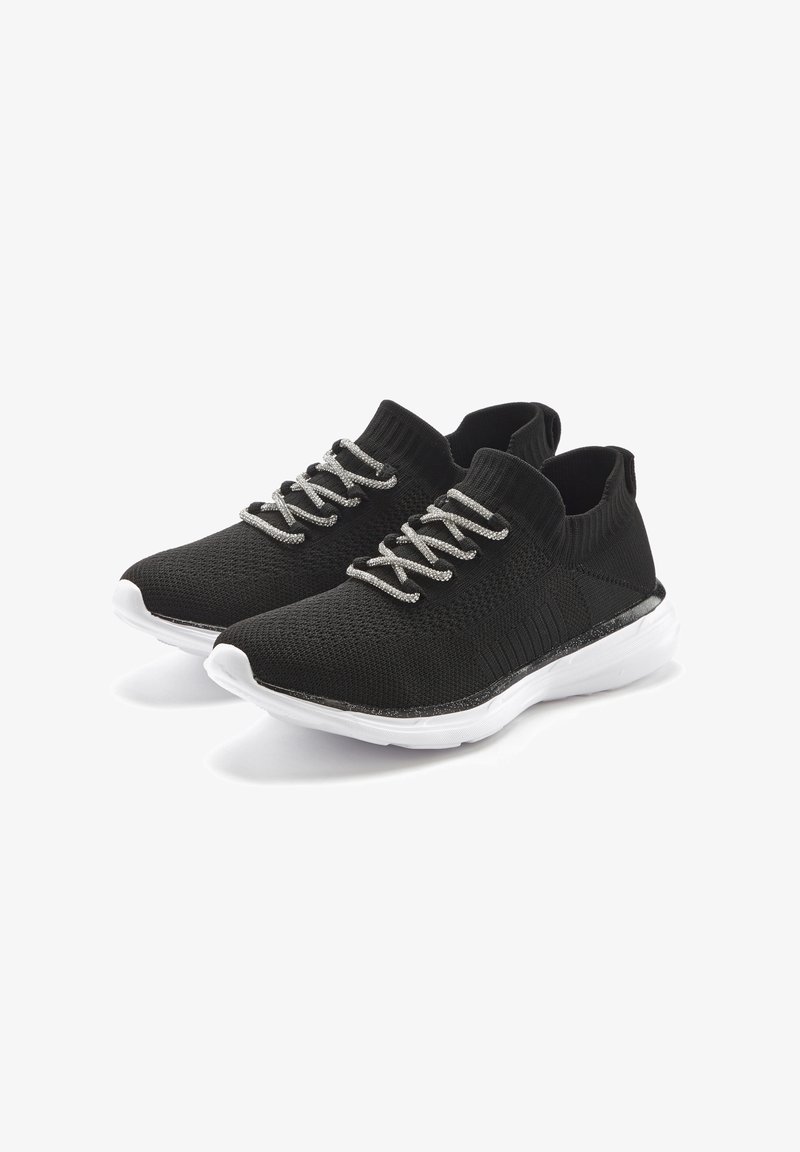 Schwarze Stricksneaker mit einer strukturierten Oberseite, elastischen Schnürsenkeln und einer weißen, gepolsterten Sohle. Merkmale einen glänzenden schwarzen Akzent entlang der Kante der Sohle.