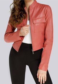 Rode leren jas met een ritssluiting, staande kraag en twee voorkzakken. Soepele textuur en getailleerd ontwerp, gecombineerd met zwarte broek.