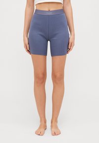 Ribota, bezšuvju, zilas velosipēdu īsās bikses ar elastīgu jostu, uz kuras attēlots Calvin Klein logo. Garums līdz vidus augšdaļai, maiga tekstūra.