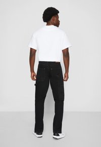 Karl Kani RETRO SLIT PANTS - Calças de ganga de perna direita - black