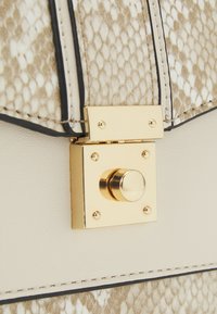 Handtas met bruin en crèmekleurig slangenhuidpatroon en een gouden vierkante sluiting, voorzien van gladde leren accenten en contrasterende donkere stiksels.