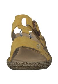 Yellow suede sandals with open toe, adjustable straps, circular brown accents, and braided rope soles. Flat design with textured footbed.